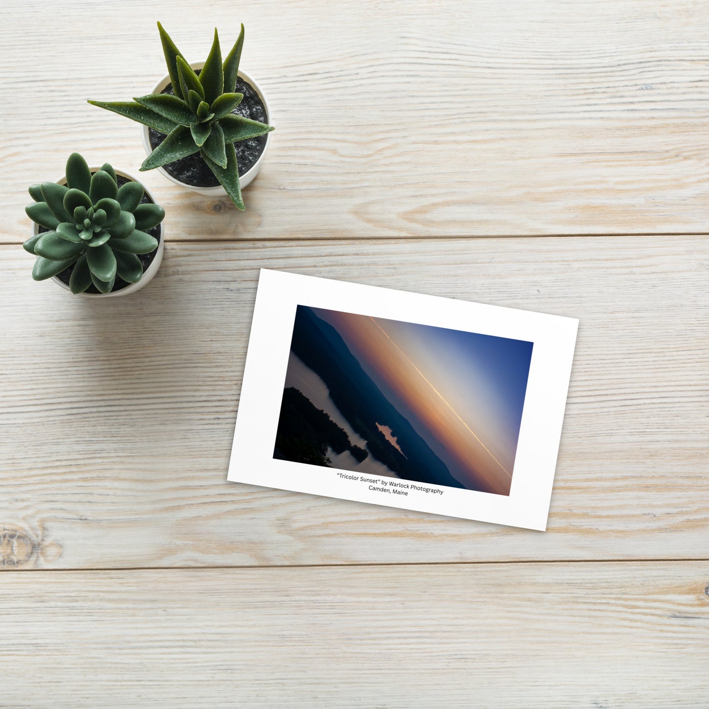 The 'Tricolor Sunset' art postcard displayed on a wooden desk next to a fountain pen, highlighting its artistic and modern energy.