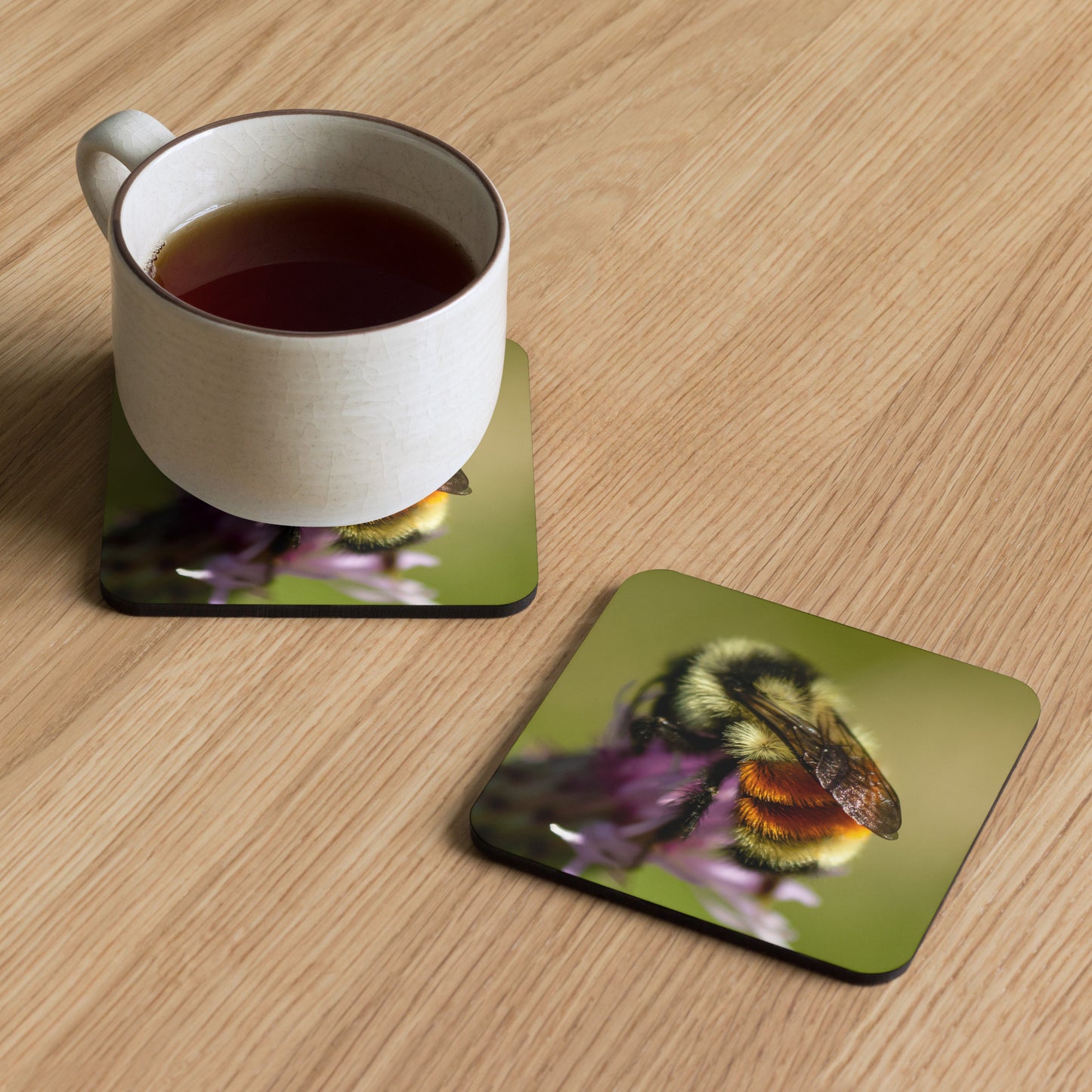 Artisan cork-back coaster titled 'Golden Hues' by Warlock Photography, featuring a macro photograph of a tricolored bumble bee on a vibrant flower.