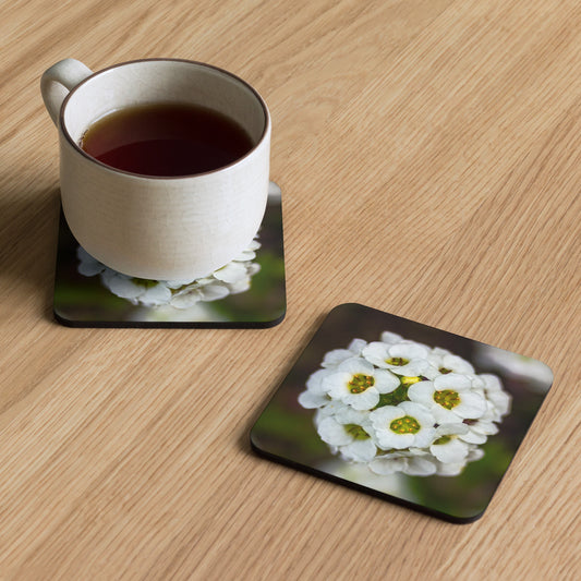 An artisan coaster titled 'Sweet Alyssum Cluster' by Warlock Photography, featuring a macro photograph of tiny white flowers with golden centers